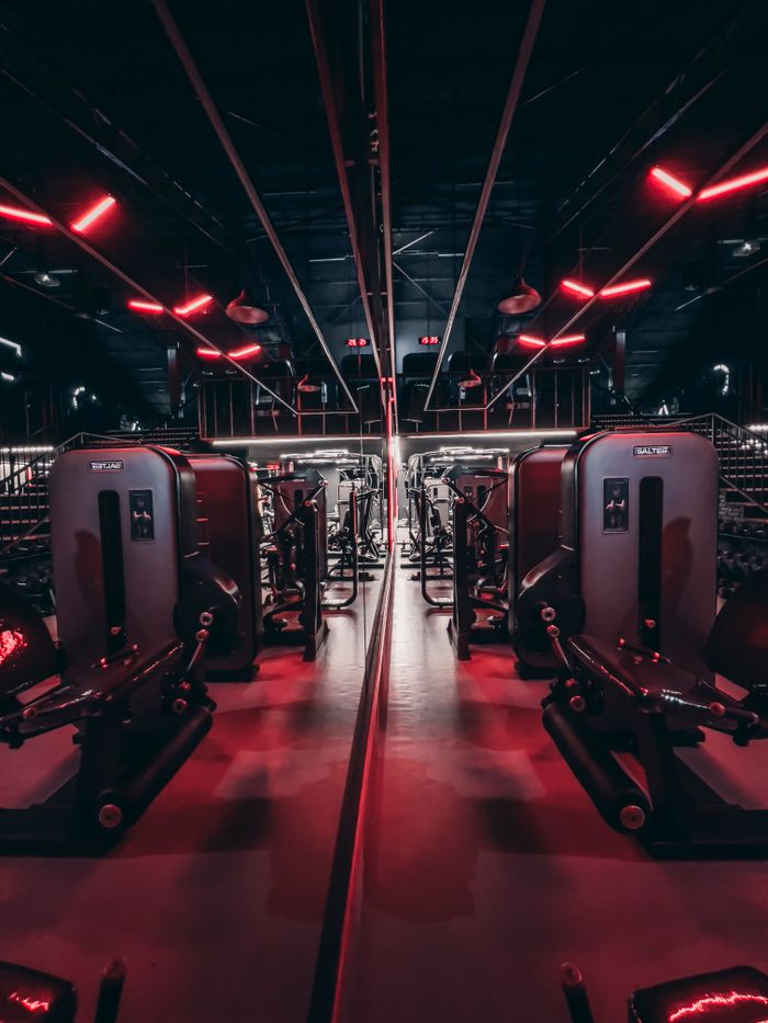 Fitness center with sleek gym equipment and red neon lights creating a futuristic ambiance.