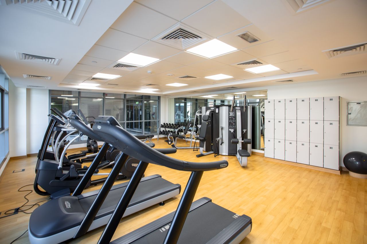 about-img-02 Spacious gym interior featuring treadmills, fitness machines, and lockers.